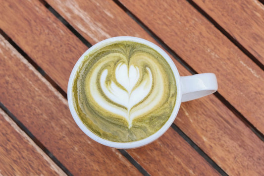 Matcha latte dans une tasse blanche sur une table en bois, vu de haut.