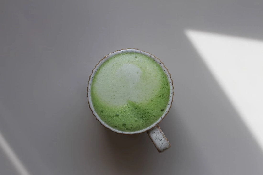 Matcha latte dans une tasse sur fond gris, vu de haut.