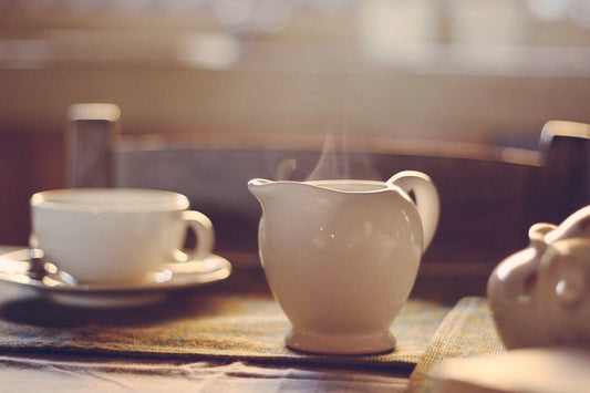 Théière en porcelaine blanche de laquelle s'échappe de la vapeur.